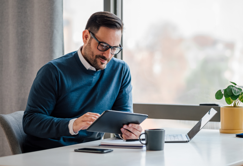 Man at desk with tablet and laptop